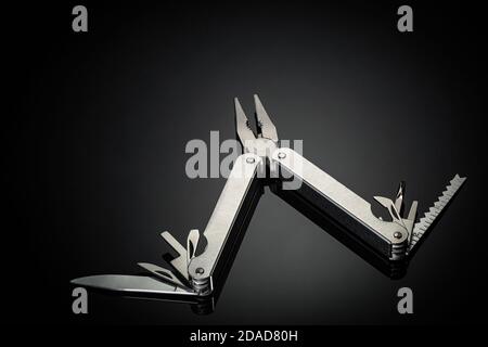 One multipurpose folding knife isolated on black background. multifunctional folding camping knife, screwdriver, scissor, knife, bottle opener, saw an Stock Photo