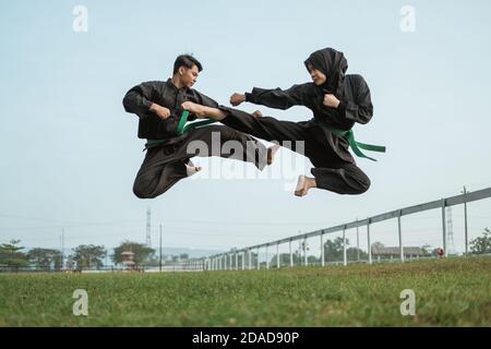 Two fighters in black pencak silat uniform fight in locks and slams in ...