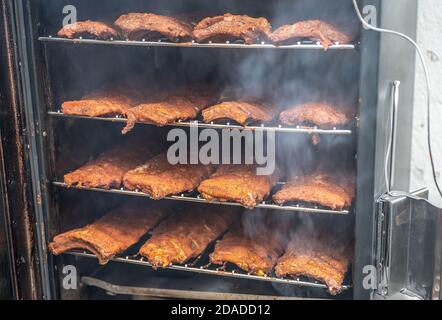 Close up on smoke rising around a slow cooked beef brisket, on a smoker barbecue in a grilling concept, with space for text on top and bottom Stock Photo