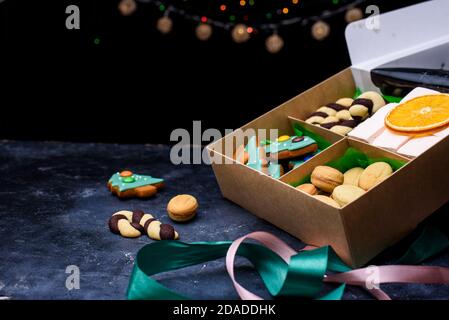 Box with satin ribbons and delicious treats for New Year and Christmas. New Year's desserts on a dark background. New Year's content