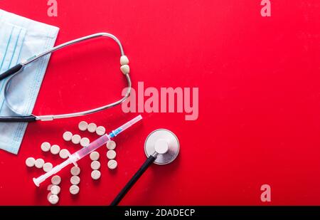 Syringe, pills, mask and stethoscope on a red background Stock Photo