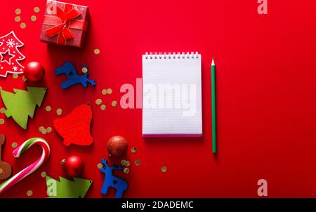 Present, gift boxes, handmade tree toy and notepad with pen for text wish, view from top, above, on redbackground, Xmas greeting card Stock Photo