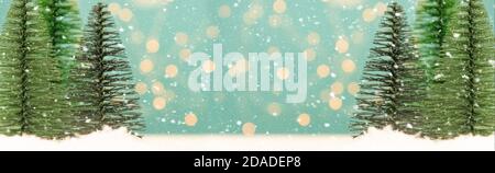 Miniature toy Christmas trees on a wooden table with snow. Imitation realistic scene. Banner. Stock Photo