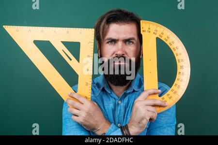formal education. measure and size. serious teacher hold triangle and protractor tool. bearded man work in classroom with ruler. prepare for geometry exam. lecturer on math lesson. back to school. Stock Photo