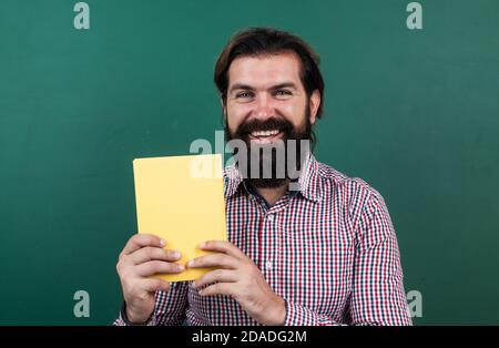 best book ever. learning the subject. happy man with beard showing the book. process of studying. nonformal education. male student in school classroom on literature lesson. pass the exam. Stock Photo