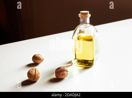 A bottle of walnut oil and three walnuts on a white background Stock Photo