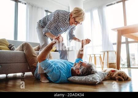 Excited mature couple having fun at home. Wife and husband spending weekend together, funny activity Stock Photo