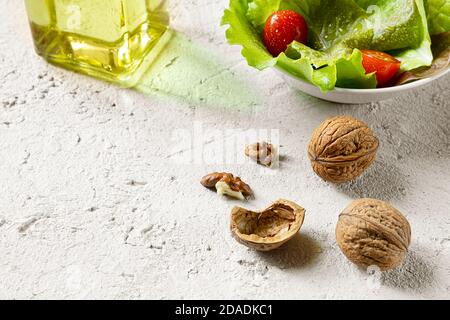 Walnuts, a bottle of walnut oil, walnuts and salad on a gray background, olive oil alternative with unique flavor Stock Photo