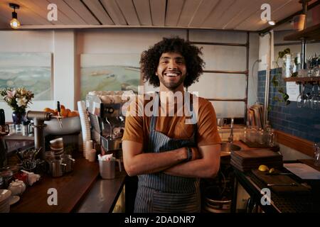 Portrait of confident male barista standing with arms crossed at coffee house Stock Photo