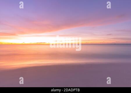 Beautiful sunset on the beach and sea. Tropical beach at beautiful sunset. Nature background. Exotic landscape, shore, coast, calm waves, soft sand Stock Photo