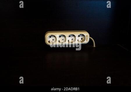 Electric dirty socket for 4 plugs on an old dark wall. Stock Photo