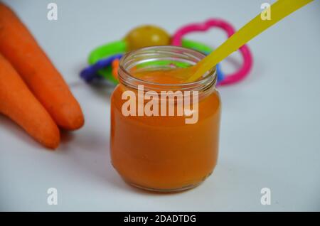 baby mashed with spoon in glass jar on white background Stock Photo