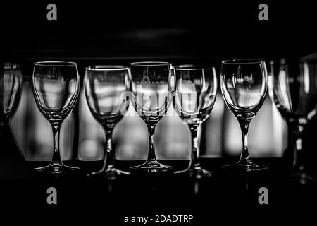 Rows of empty wine glasses on shelf, dramatic black and white process Stock Photo