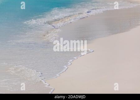 Blue ocean waves sunlight reflection sand beach background. Calm waves splashing on white sand, sunny tropical weather, summer vibes Stock Photo