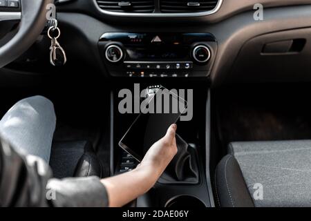 Interior view of a modern new car. A young woman using smartphone while driving the car Stock Photo