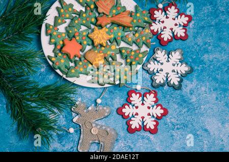 Plate with handmade Christmas gingerbread, pine branches and Christmas decorations on a blue background. Horizontal orientation. Stock Photo