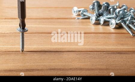 The screwdriver twists the self-cut into wooden boards. Construction tools, home repairs. Stock Photo