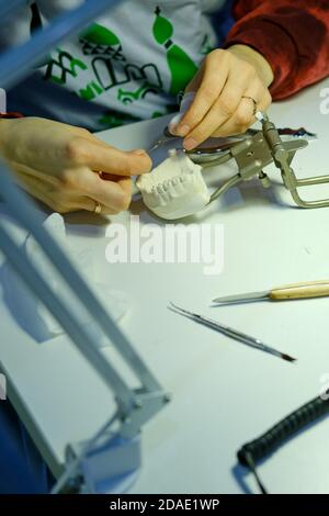 The dentist's hands are working on making prosthetic teeth to replace the patient Stock Photo