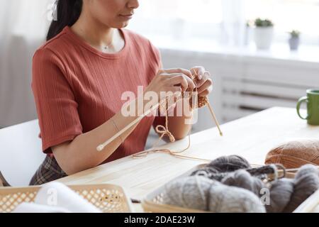 Close-up of young woman using wool for knitting she sitting at the table and doing her work Stock Photo