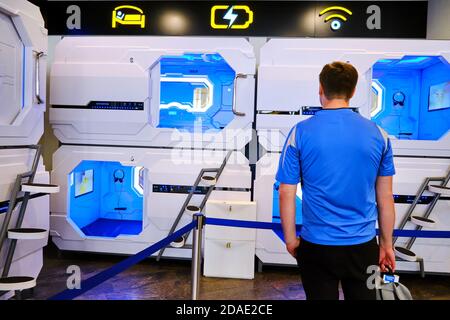 A man stands in front of a capsule hotel for travelers. Aerosleep capsule hotel open entrance hole with inside interior - Sheremetievo airport, Moscow Stock Photo