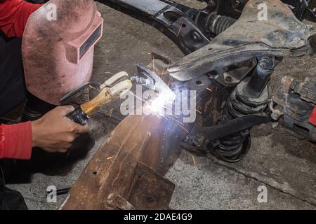 Hand of Welder Welding Metal or Steel of Car Construction in Garage on Top View Stock Photo