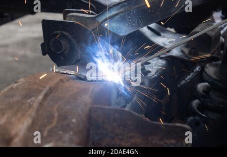 Welder Welding Bottom Car Chassis by Electric Welding Torch in Close Up View Stock Photo