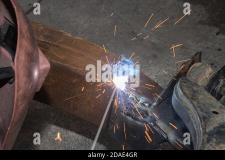 Welder Welding Bottom Car Chassis by Electric Welding Torch on Top Angle View Stock Photo
