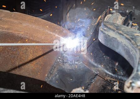 Welder Welding Bottom Car Chassis by Electric Welding Torch in Zoom View Stock Photo