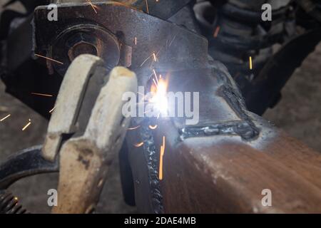 Welding Man Welding Bottom Construction of Car Chassis in Garage in Zoom View Stock Photo