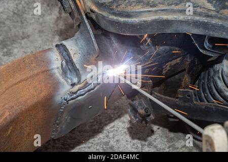 Welder Welding Bottom Car Chassis by Electric Welding Torch on Top Left View Stock Photo