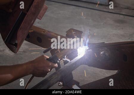 Hand of Welding Worker Hold Welding Mask and Welding Metal or Steel Construction of Car in Garage Stock Photo