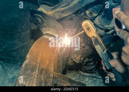 Welder Welding Bottom Car Chassis by Electric Welding Torch at Side View in Vintage Tone Stock Photo