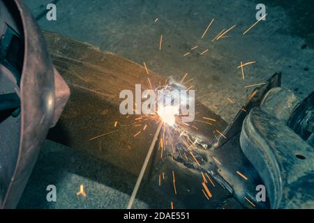 Welder Welding Bottom Car Chassis by Electric Welding Torch on Top Angle View in Vintage Tone Stock Photo