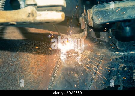 Welder Welding Bottom Car Chassis by Electric Welding Torch on Center Frame in Vintage Tone Stock Photo