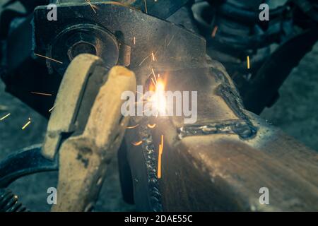 Welding Man Welding Bottom Construction of Car Chassis in Garage in Zoom View in Vintage Tone Stock Photo