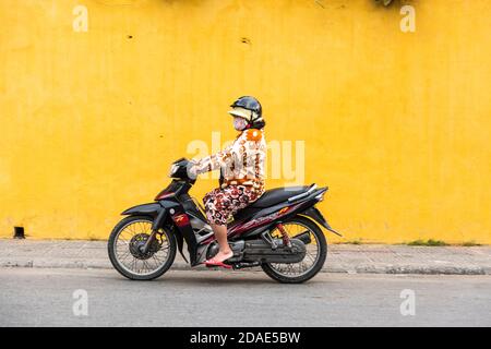 Hoi An Ancient Town, Vietnam, January 27, 2020 - Woman riding a scooter with helmet in a street at Hoi An Ancient Town Stock Photo