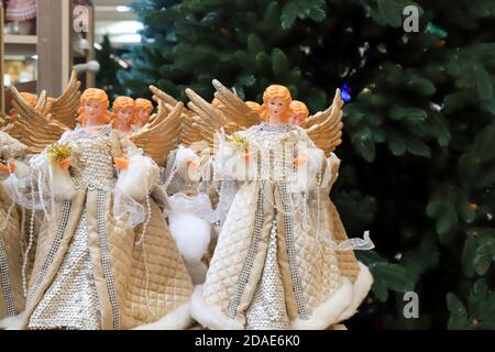 Christmas angels with wings, beautiful New Year decorations and gifts on the background of a Christmas tree in the store. Festive winter shopping in Stock Photo