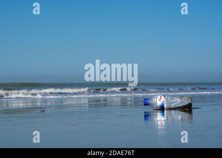 Ocean pollution by junk toxic consumer plastics and single use plastic bottle washed ashore by wave Stock Photo