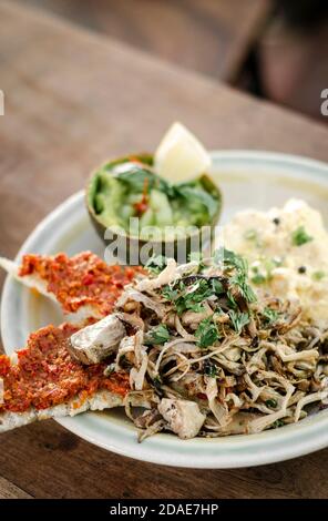 modern mexican brunch of  fried mushrooms with guacamole and spicy red pepper paste toast and scrambled eggs Stock Photo