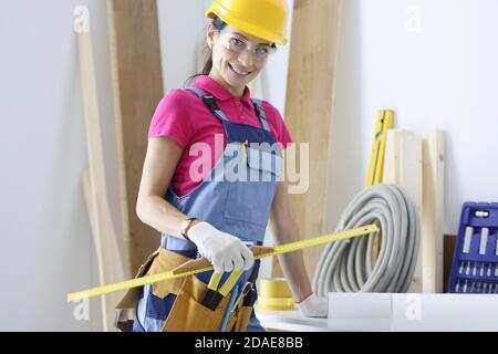 Woman builder in protective helmet and glasses holding ruler Stock Photo