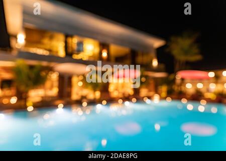 Blur lights reflection in infinity swimming luxury pool party water at night background. Resort hotel abstract bokeh background summer travel vacation Stock Photo