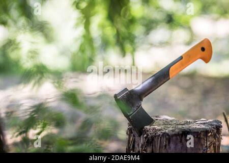 Axe stuck in wood. Axe in the stump blurred forest nature, ground background Stock Photo