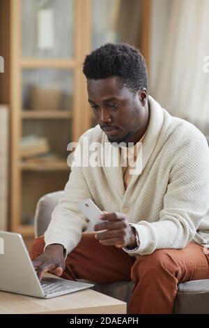 African young man sitting in front of the laptop and doing shopping online using his credit card Stock Photo