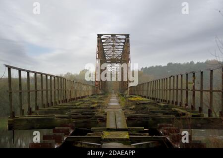 Old steel riveted bridge. Destroyed and forgotten river crossing. Old engineering. Stock Photo