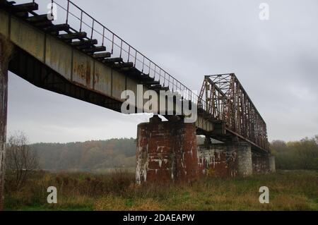 Old steel riveted bridge. Destroyed and forgotten river crossing. Old engineering. Stock Photo