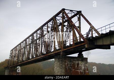 Old steel riveted bridge. Destroyed and forgotten river crossing. Old engineering. Stock Photo