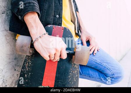 Close up of young man hands holding used trendy skateboard - concept of young people and urban lifestyle - alternative life for teen man - unrecognizable caucasian people in urban concept life Stock Photo