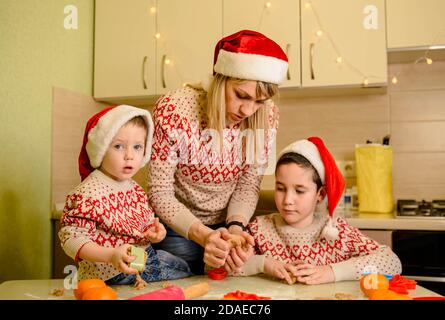 Mother and kids making gingerbread house on Christmas. Tasty dessert Stock Photo