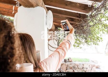 Mixed race female couple in pajama make self portrait with smartphone in the garden just woken up - Homosexual women couple in vacation using social n Stock Photo