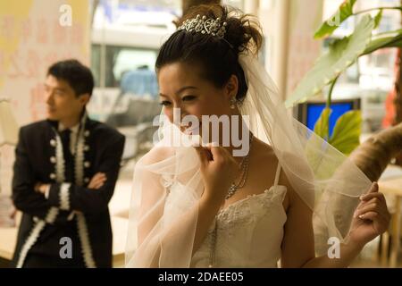 BEIJING, CHINA - JUNE 2006:   Li Xiao Ang, 26, a company consultant, and his bride-to-be LI Yue, 27 who works in an advertising agency, wear their final costumes after a day long session at Miracle Love. Stock Photo
